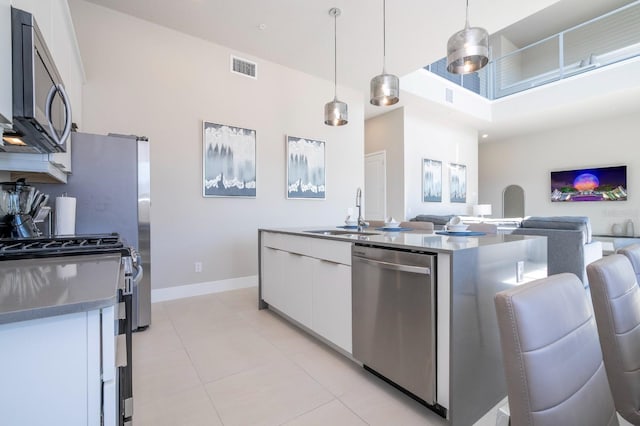 kitchen featuring sink, stainless steel appliances, white cabinets, pendant lighting, and light tile patterned flooring