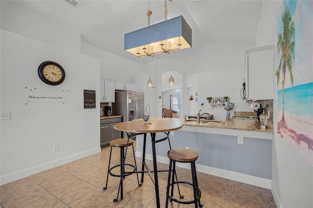 kitchen featuring hanging light fixtures, kitchen peninsula, lofted ceiling, a kitchen bar, and white cabinets