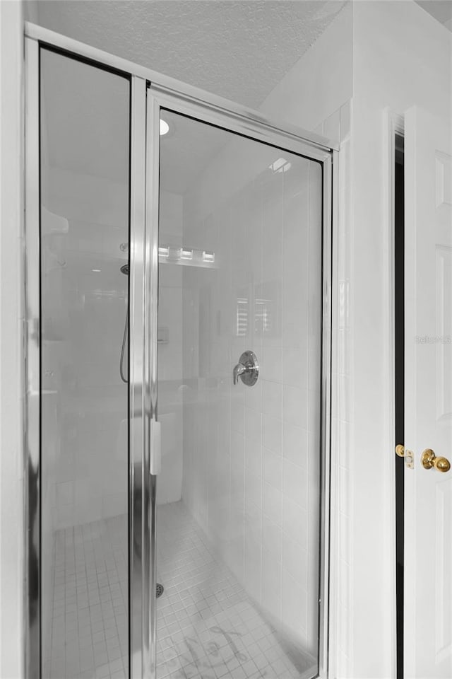 bathroom with an enclosed shower and a textured ceiling