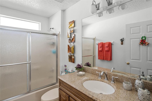 full bathroom with vanity, toilet, shower / bath combination with glass door, and a textured ceiling