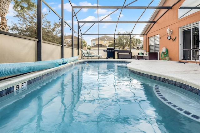 view of pool with glass enclosure and a patio