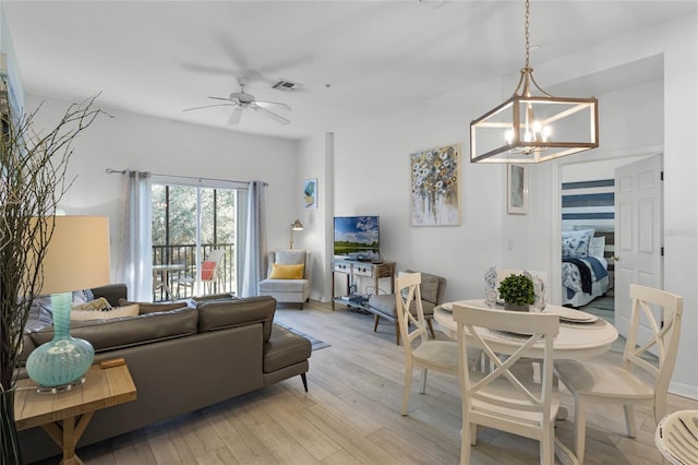 living room featuring light hardwood / wood-style flooring and ceiling fan with notable chandelier