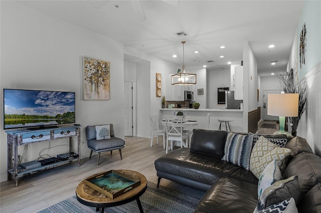 living room featuring a chandelier and light hardwood / wood-style flooring