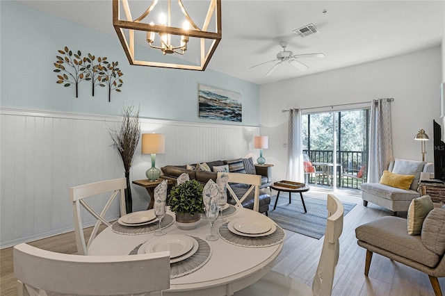 dining room featuring ceiling fan with notable chandelier and light hardwood / wood-style floors