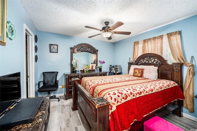 bedroom with a textured ceiling, light hardwood / wood-style flooring, and ceiling fan