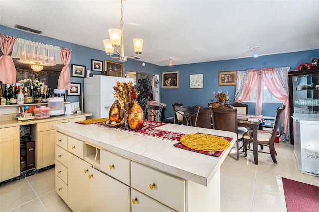 kitchen featuring a center island, light tile patterned floors, a chandelier, and a textured ceiling