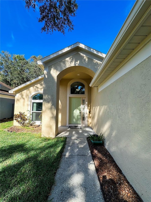 view of exterior entry featuring a lawn