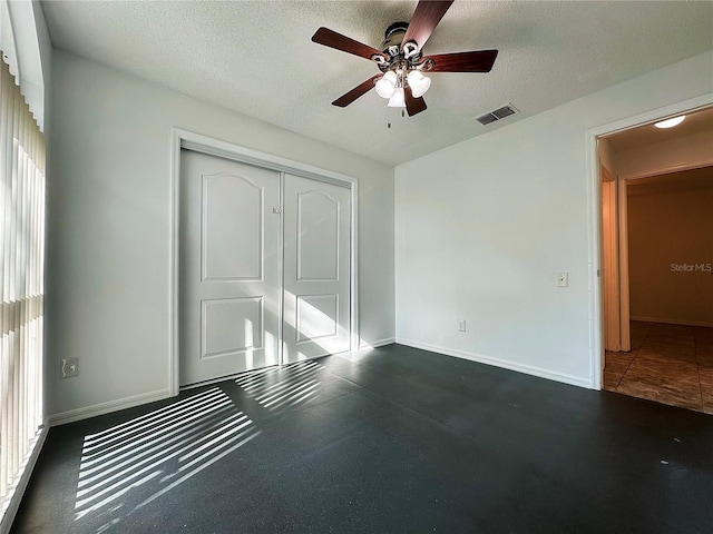 unfurnished bedroom featuring multiple windows, ceiling fan, a closet, and a textured ceiling