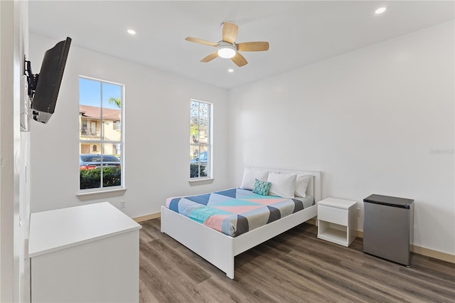 bedroom featuring hardwood / wood-style flooring, ceiling fan, refrigerator, and multiple windows