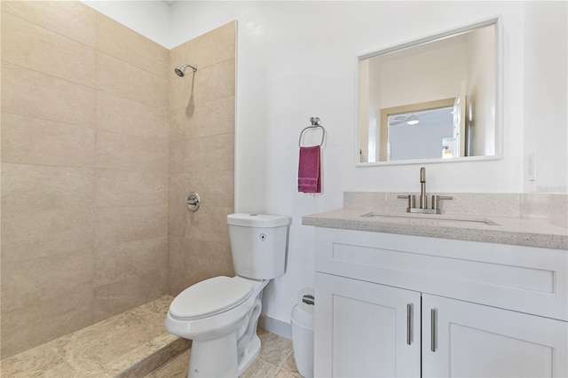 bathroom featuring a tile shower, vanity, and toilet