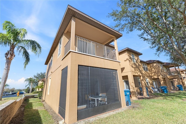 exterior space with a balcony, a lawn, and stucco siding