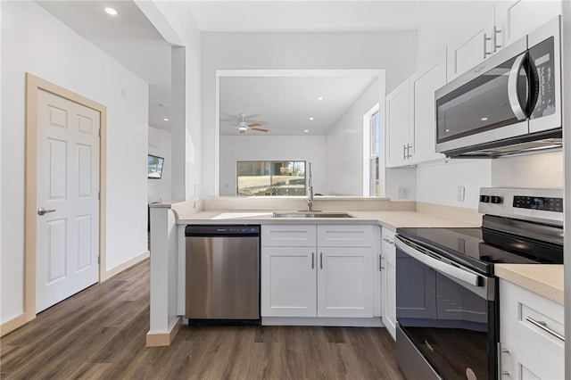 kitchen with white cabinets, appliances with stainless steel finishes, dark wood-type flooring, light countertops, and a sink