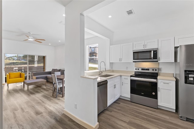 kitchen with stainless steel appliances, light countertops, visible vents, white cabinets, and a sink