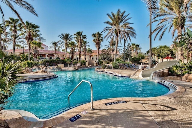 community pool featuring a water slide and a patio area