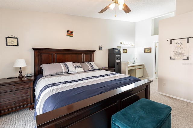 bedroom with ensuite bath, ceiling fan, light carpet, and a textured ceiling