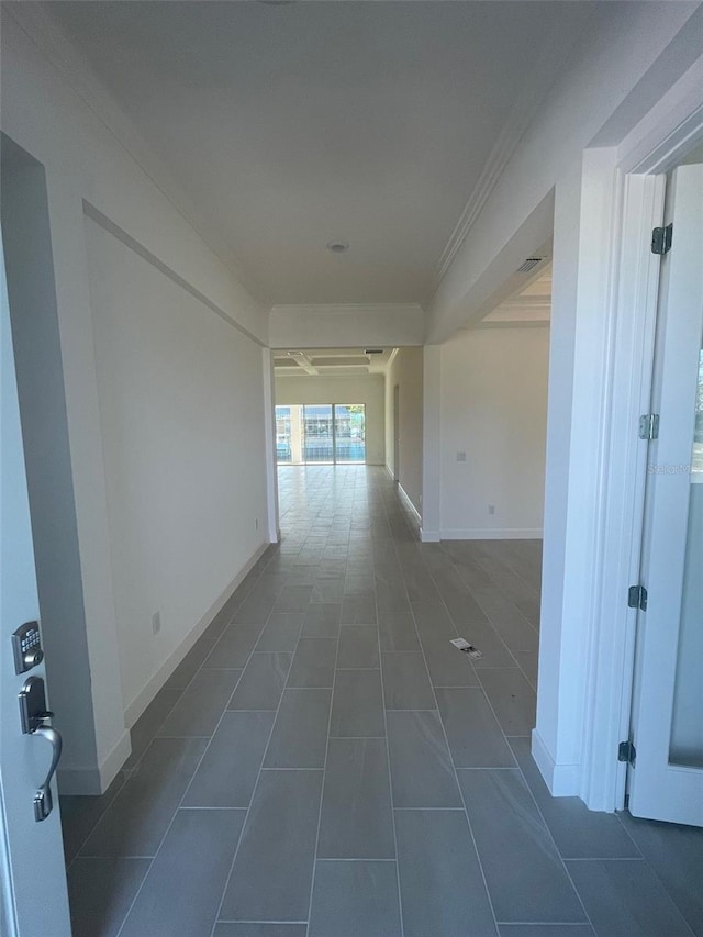 hallway with crown molding and dark tile patterned floors