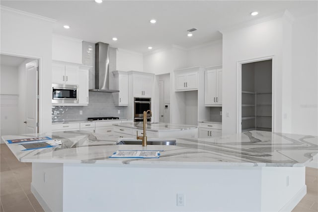 kitchen featuring white cabinetry, appliances with stainless steel finishes, wall chimney exhaust hood, and a spacious island