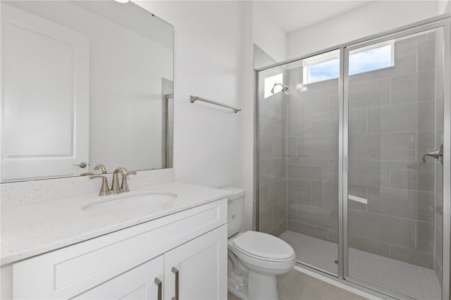 bathroom featuring vanity, tile patterned flooring, toilet, and walk in shower