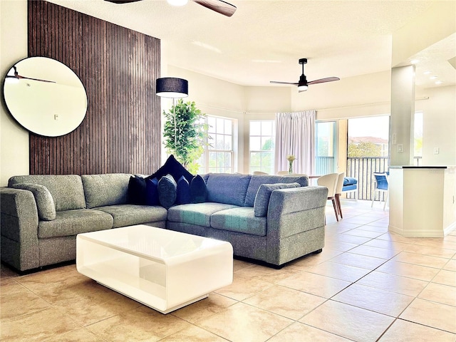 living room featuring light tile patterned floors, a textured ceiling, and ceiling fan