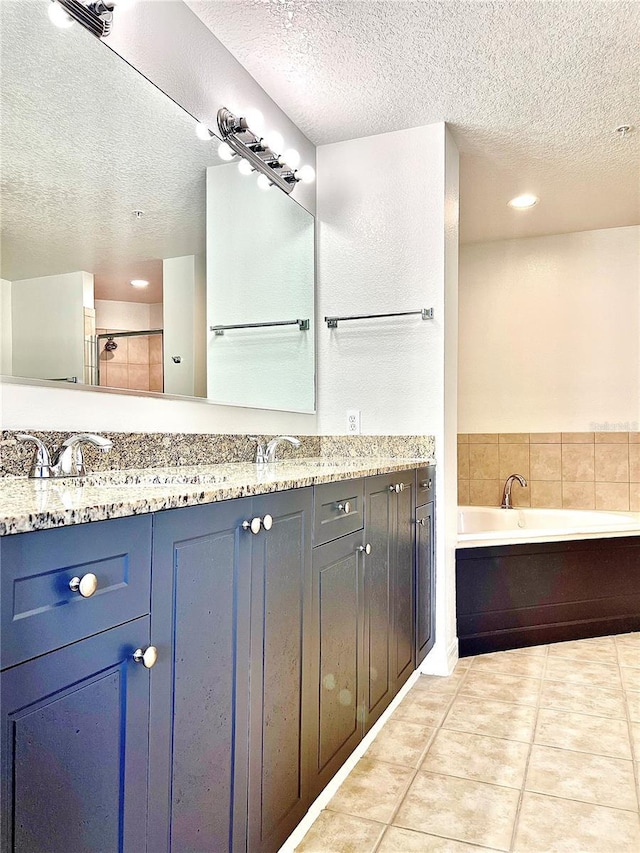 bathroom with tile patterned floors, vanity, a textured ceiling, and a tub