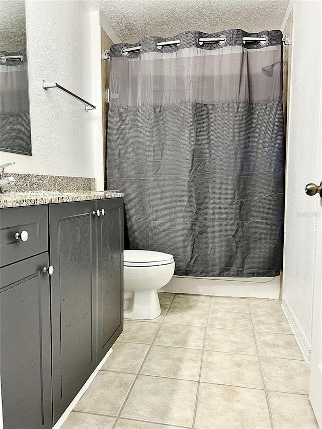 bathroom with tile patterned floors, vanity, a textured ceiling, and toilet