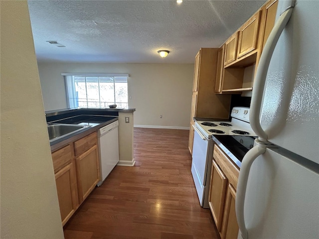 kitchen featuring white appliances, dark wood-style floors, visible vents, a sink, and dark countertops