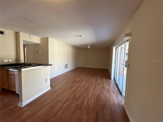 unfurnished living room featuring ceiling fan, sink, a textured ceiling, and hardwood / wood-style flooring