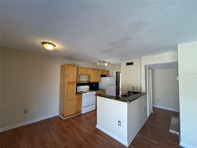 kitchen with white appliances, dark countertops, a peninsula, and dark wood-style flooring