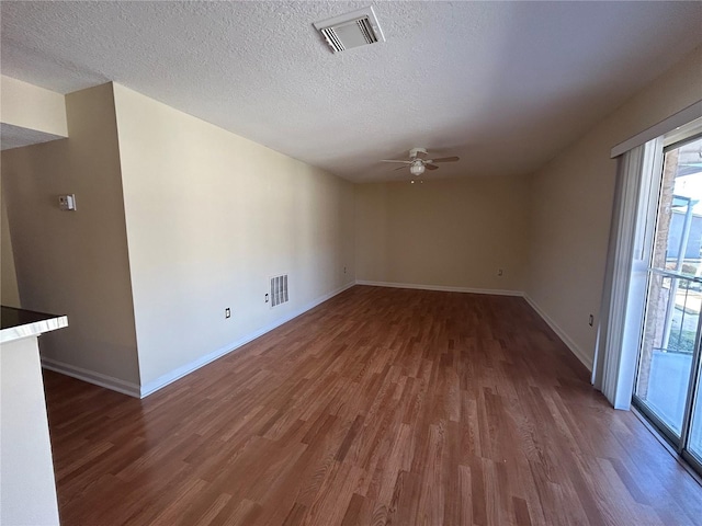 empty room featuring visible vents, a textured ceiling, wood finished floors, and a ceiling fan