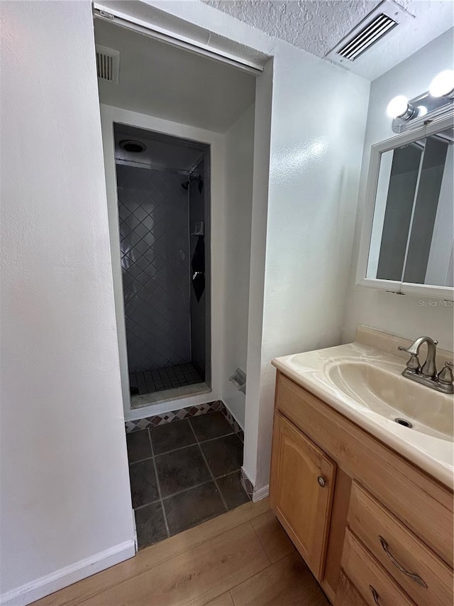 bathroom featuring visible vents, a stall shower, tile patterned flooring, baseboards, and vanity