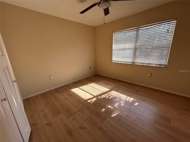 spare room with wood finished floors, a ceiling fan, and baseboards