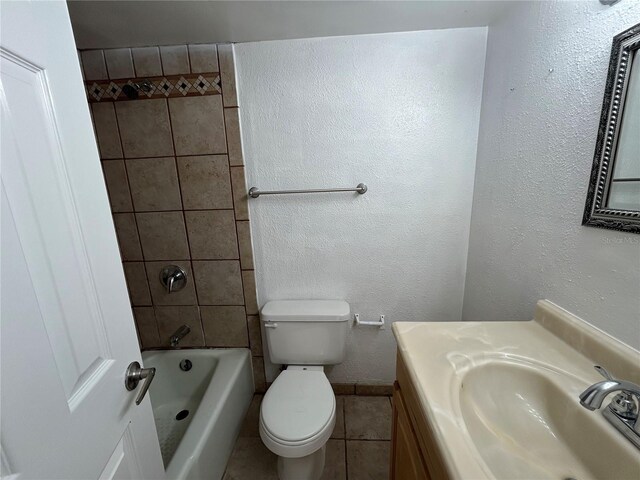 bathroom featuring baseboards, toilet, bathing tub / shower combination, a textured wall, and vanity