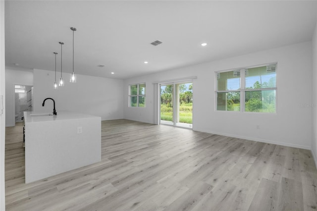 unfurnished living room featuring sink and light hardwood / wood-style floors