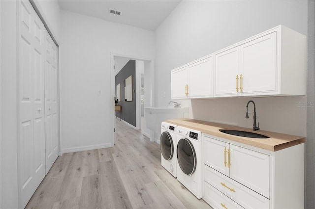 laundry area with cabinets, independent washer and dryer, light hardwood / wood-style flooring, and sink