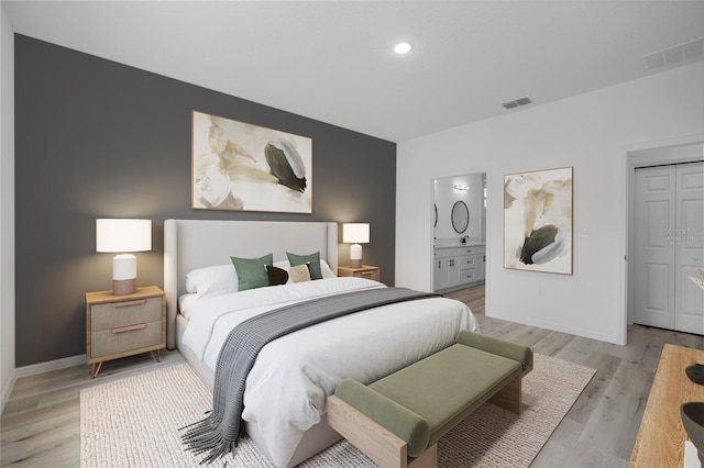 bedroom featuring light hardwood / wood-style floors, connected bathroom, and a closet