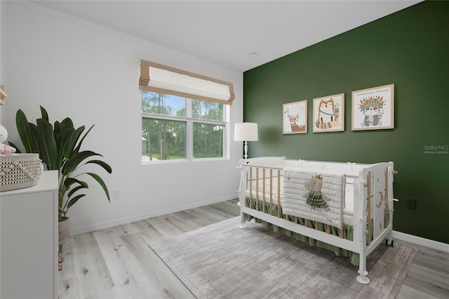 bedroom featuring light hardwood / wood-style floors and a nursery area