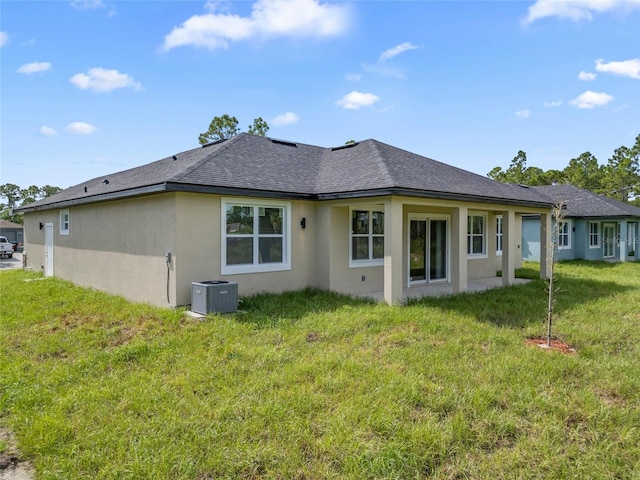 rear view of property featuring cooling unit and a lawn