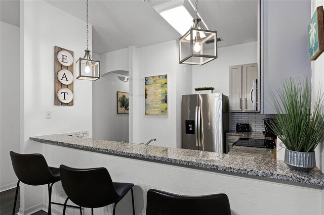 608 Gran Bahama Blvd Unit 608, Davenport, FL 33897 - kitchen with stainless steel appliances, decorative backsplash, a peninsula, light stone counters, and arched walkways