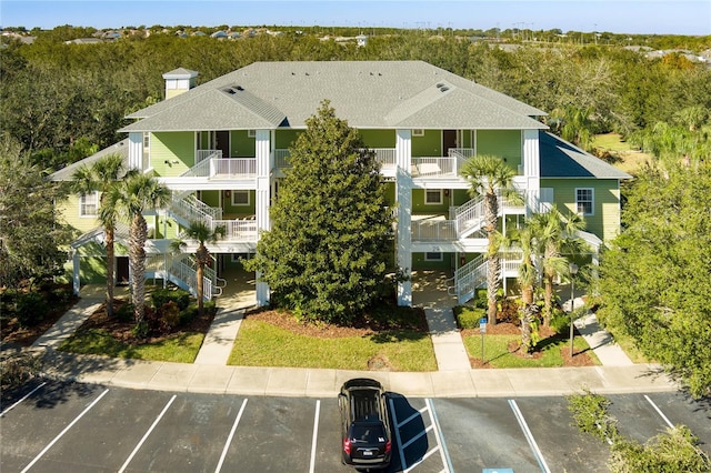 view of property with stairs and uncovered parking