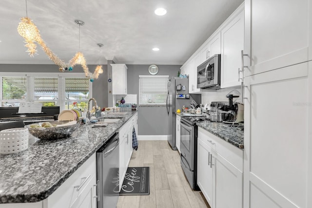 kitchen with decorative light fixtures, stainless steel appliances, white cabinets, and sink