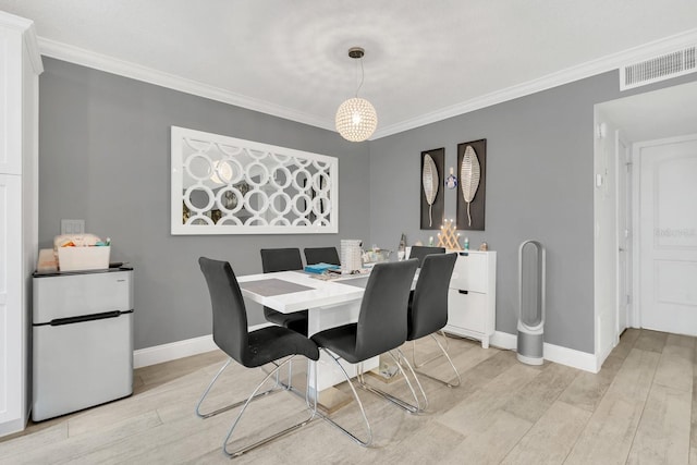 dining space featuring light hardwood / wood-style floors and crown molding