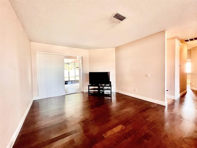 unfurnished living room with a textured ceiling and dark hardwood / wood-style floors