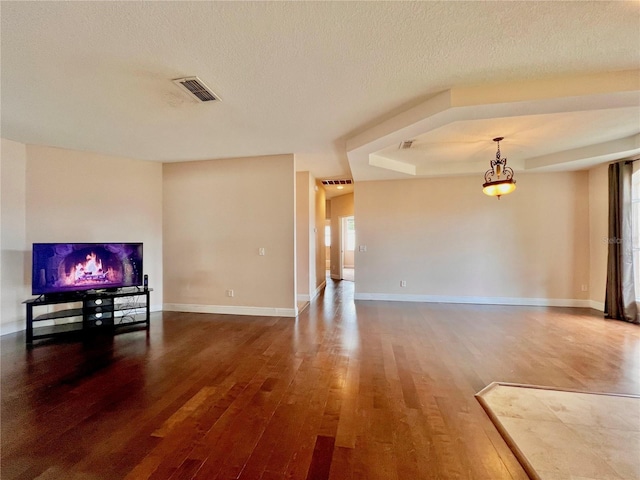 unfurnished living room featuring a raised ceiling, hardwood / wood-style floors, and a textured ceiling