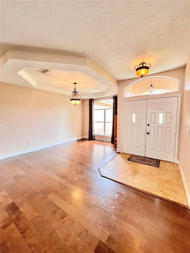 entrance foyer featuring a textured ceiling and a tray ceiling