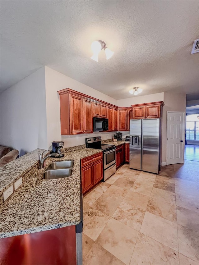 kitchen featuring kitchen peninsula, appliances with stainless steel finishes, light stone countertops, and sink