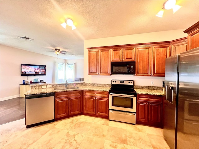 kitchen featuring kitchen peninsula, light stone countertops, a textured ceiling, stainless steel appliances, and sink