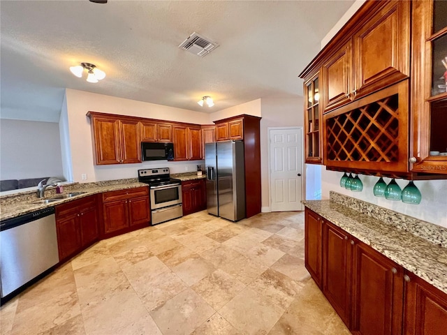 kitchen featuring light stone counters, sink, and appliances with stainless steel finishes