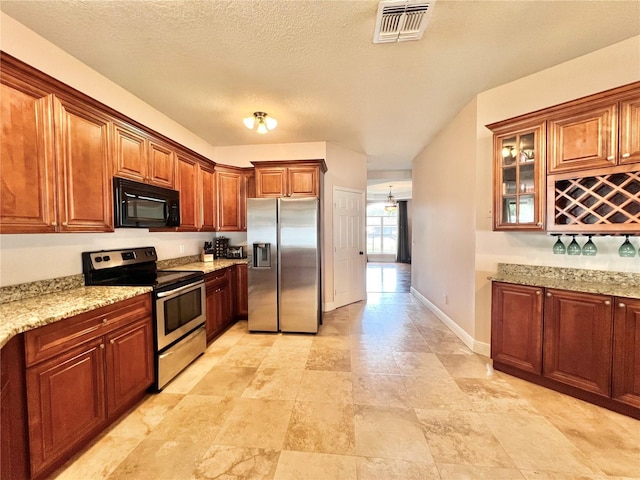 kitchen with light stone counters, a textured ceiling, and appliances with stainless steel finishes