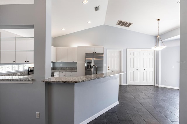 kitchen featuring stainless steel fridge, white cabinets, pendant lighting, and lofted ceiling