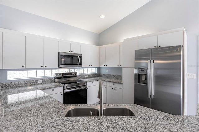 kitchen featuring stone counters, white cabinetry, lofted ceiling, and appliances with stainless steel finishes